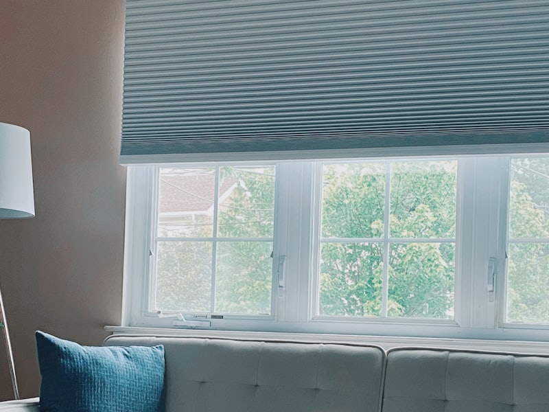 Cellular honeycomb shade lowered halfway across a bright living room window